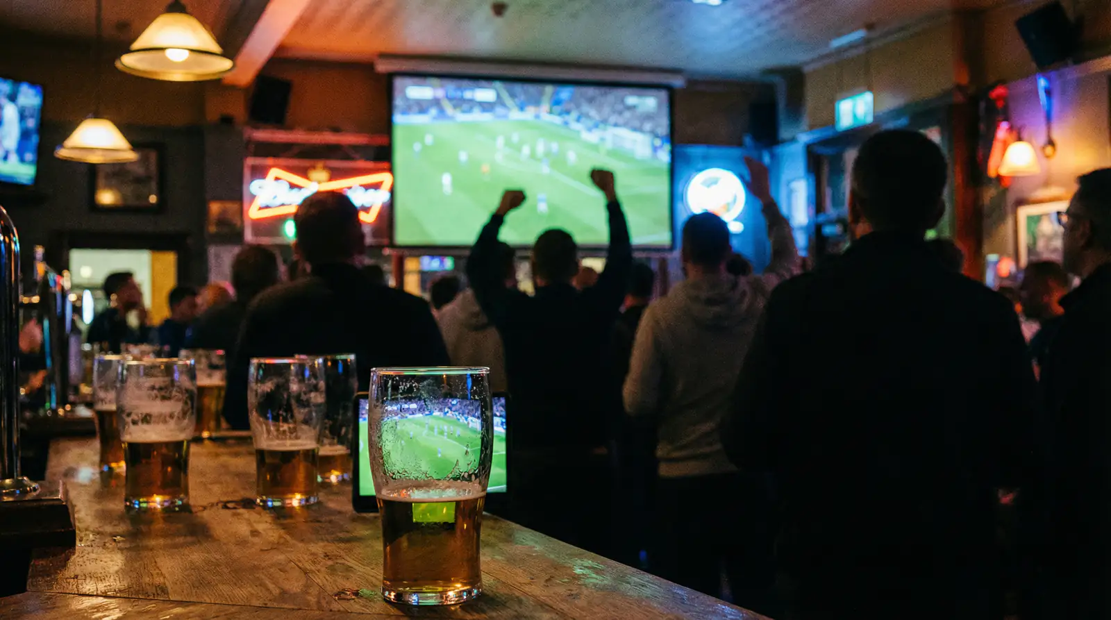 Football fans in a pub watching a World Cup match on a large screen